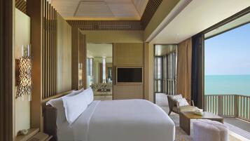Habitación de hotel con una cama grande, televisión, balcón con vista al mar y una zona de estar con vista al océano.