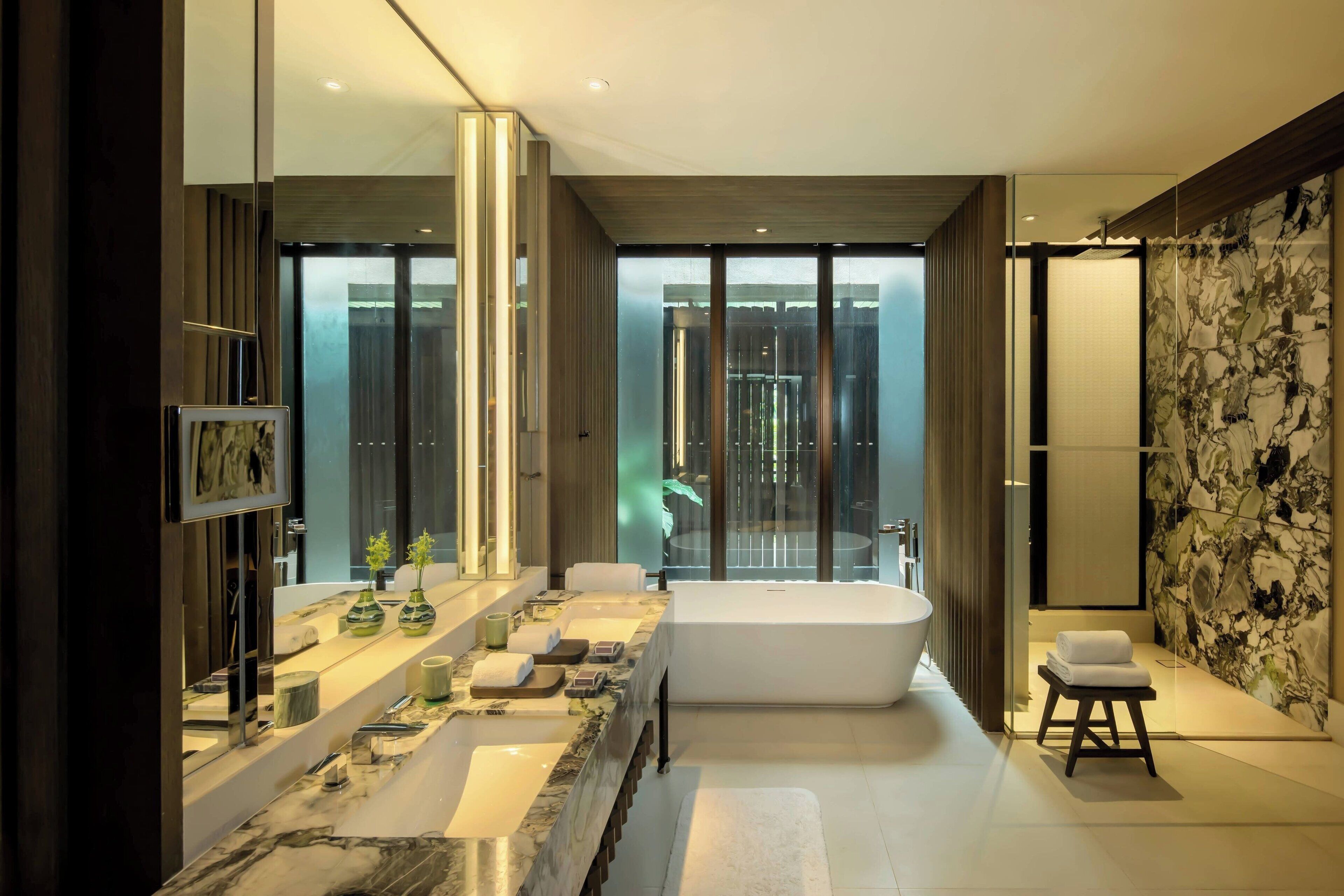Ein modernes Badezimmer mit einer großzügigen Badewanne, einem Waschtisch mit mehreren Waschbecken und einem großen Spiegel.
