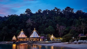 A beachfront resort with multiple dome-shaped structures, a sandy beach, and a forested hillside in the background. - The Ritz-Carlton, Langkawi (Langkawi)