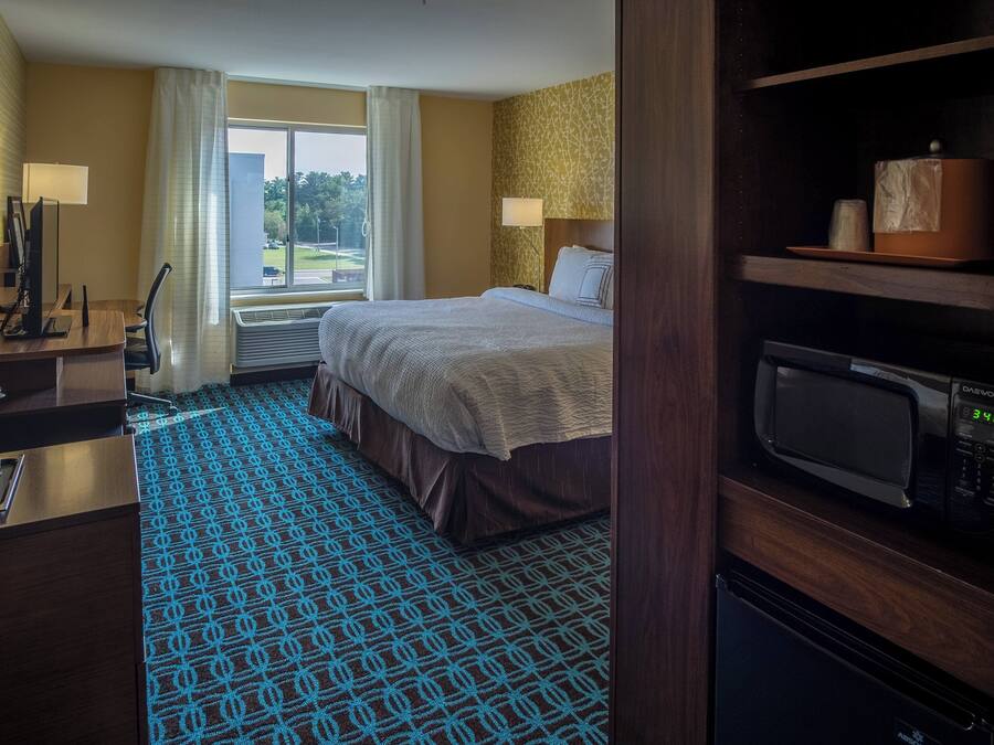 Ein Hotelzimmer mit Bett, Schreibtisch mit Computer, Mikrowelle und Blick ins Freie.