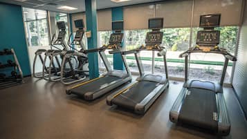 Une salle de sport équipée de tapis de course, d’appareils de musculation et d’haltères.