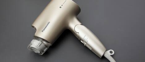 Un secador de pelo Panasonic con acabado metálico y boquilla transparente, que incluye un cable de alimentación con un enchufe de muelle.