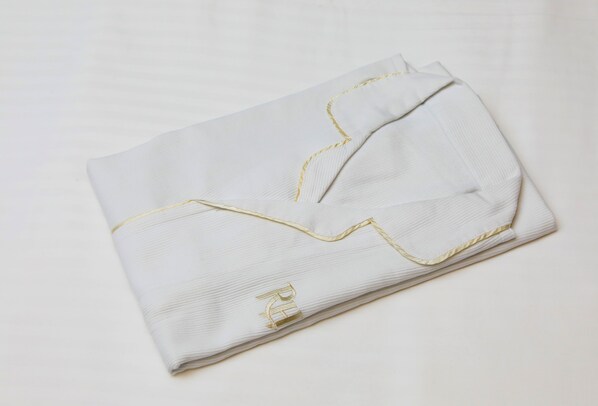 A neatly folded white garment with gold embroidery on the collar and hem.