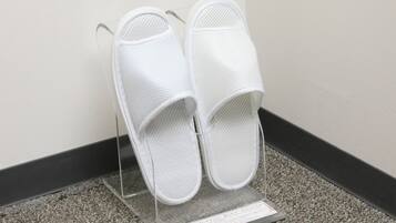 A pair of white slippers on a clear stand with a small sign.
