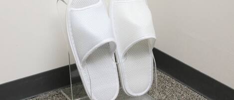 A pair of white slippers on a clear stand with a small sign.