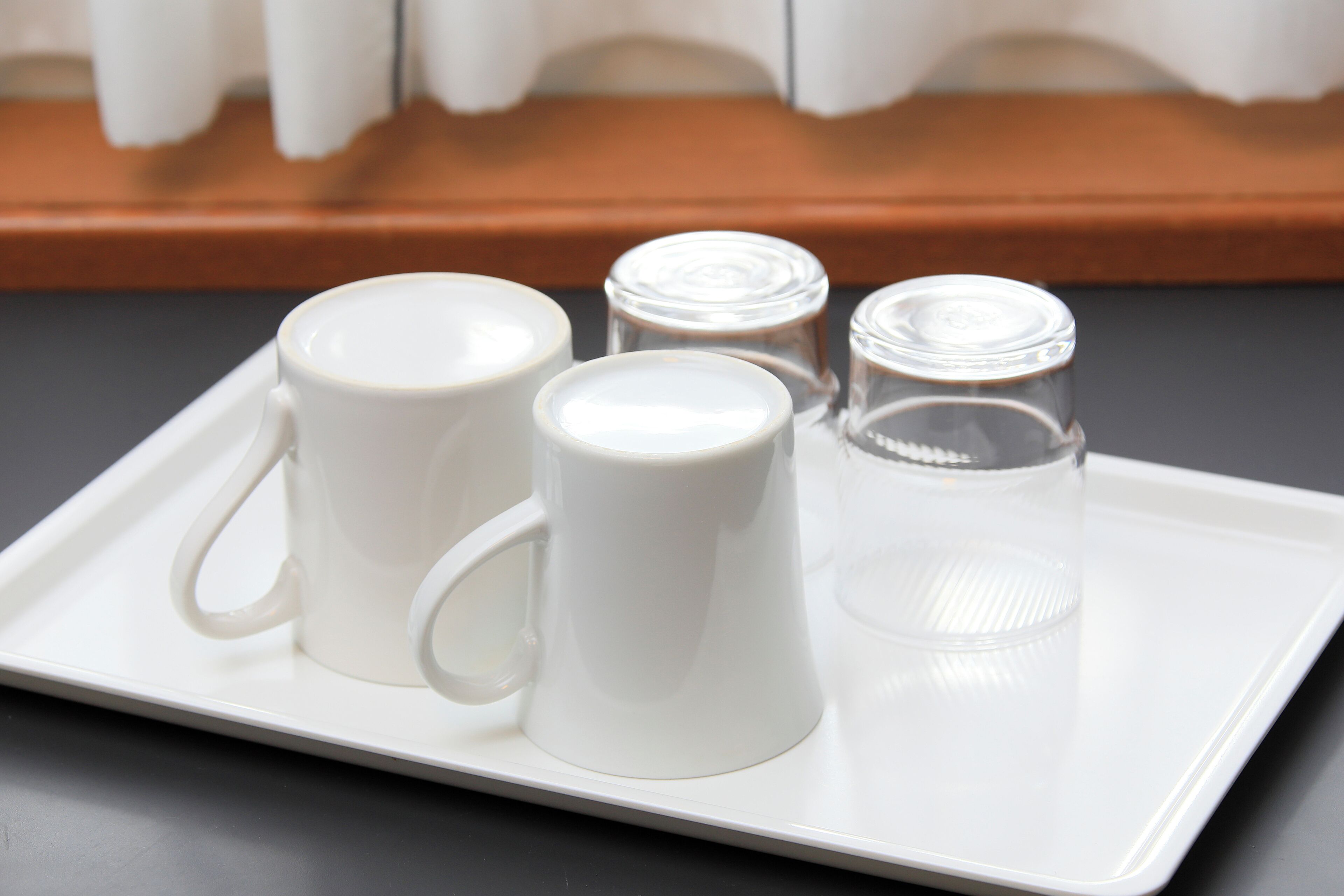 Una bandeja con tres tazas blancas de cerámica y dos recipientes de vidrio.
