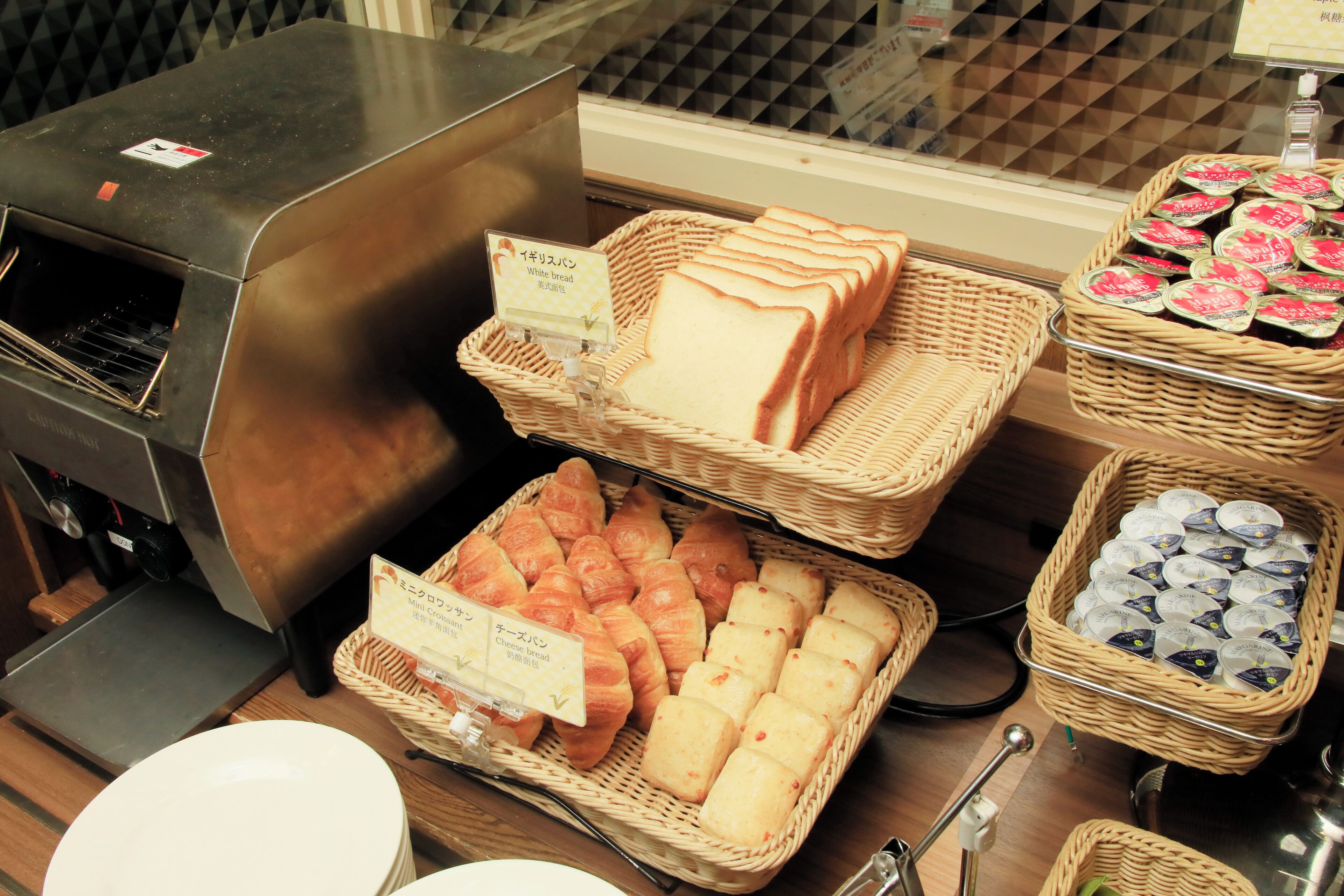 A bakery display with various breads and pastries, a coffee machine, and baskets of items.