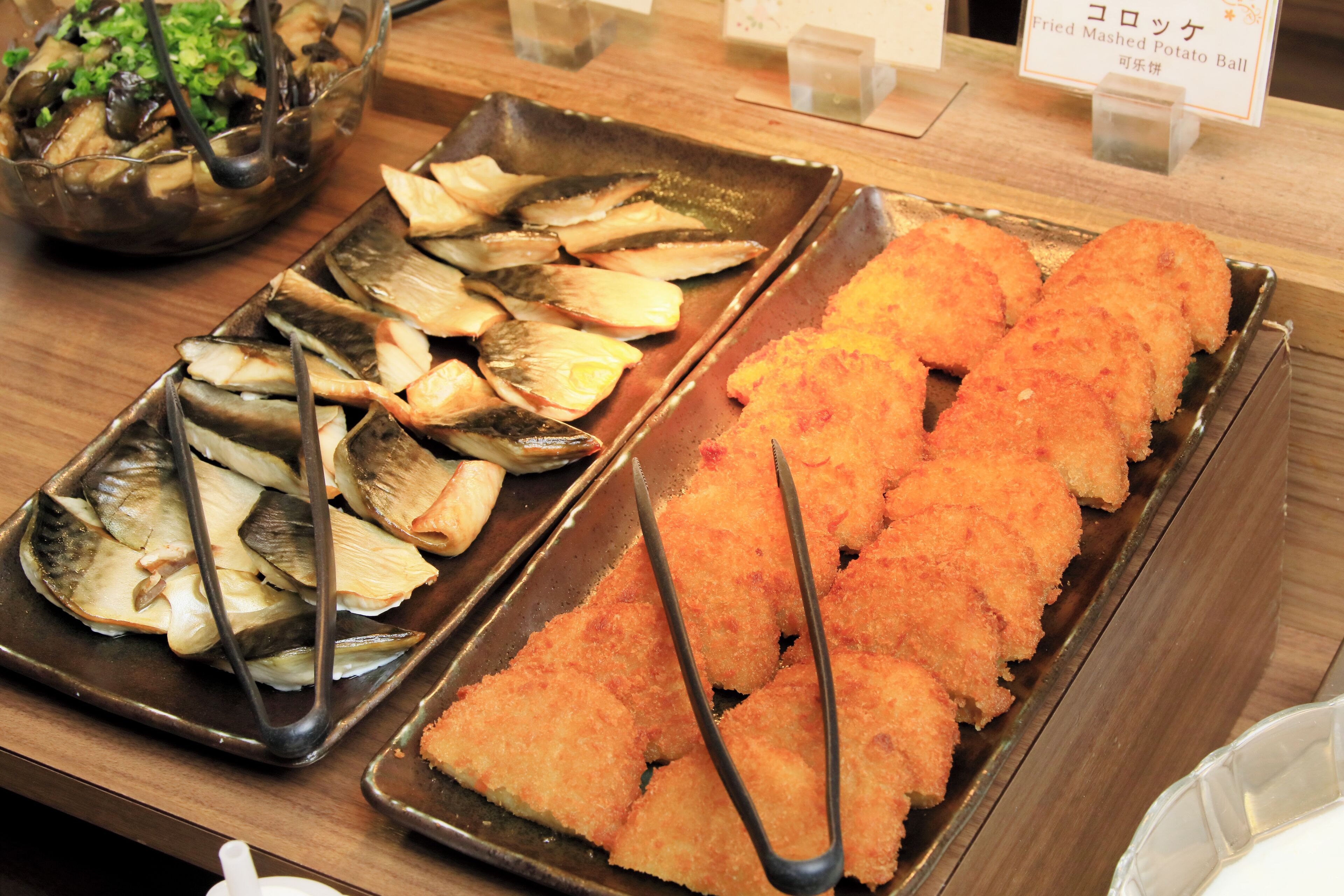 Een buffet met diverse gerechten, waaronder gebakken vis en andere bereide maaltijden.