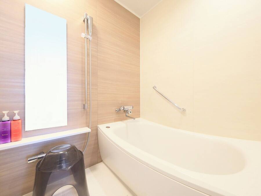 A modern bathroom with a large bathtub, a shower, and a vanity with toiletries.