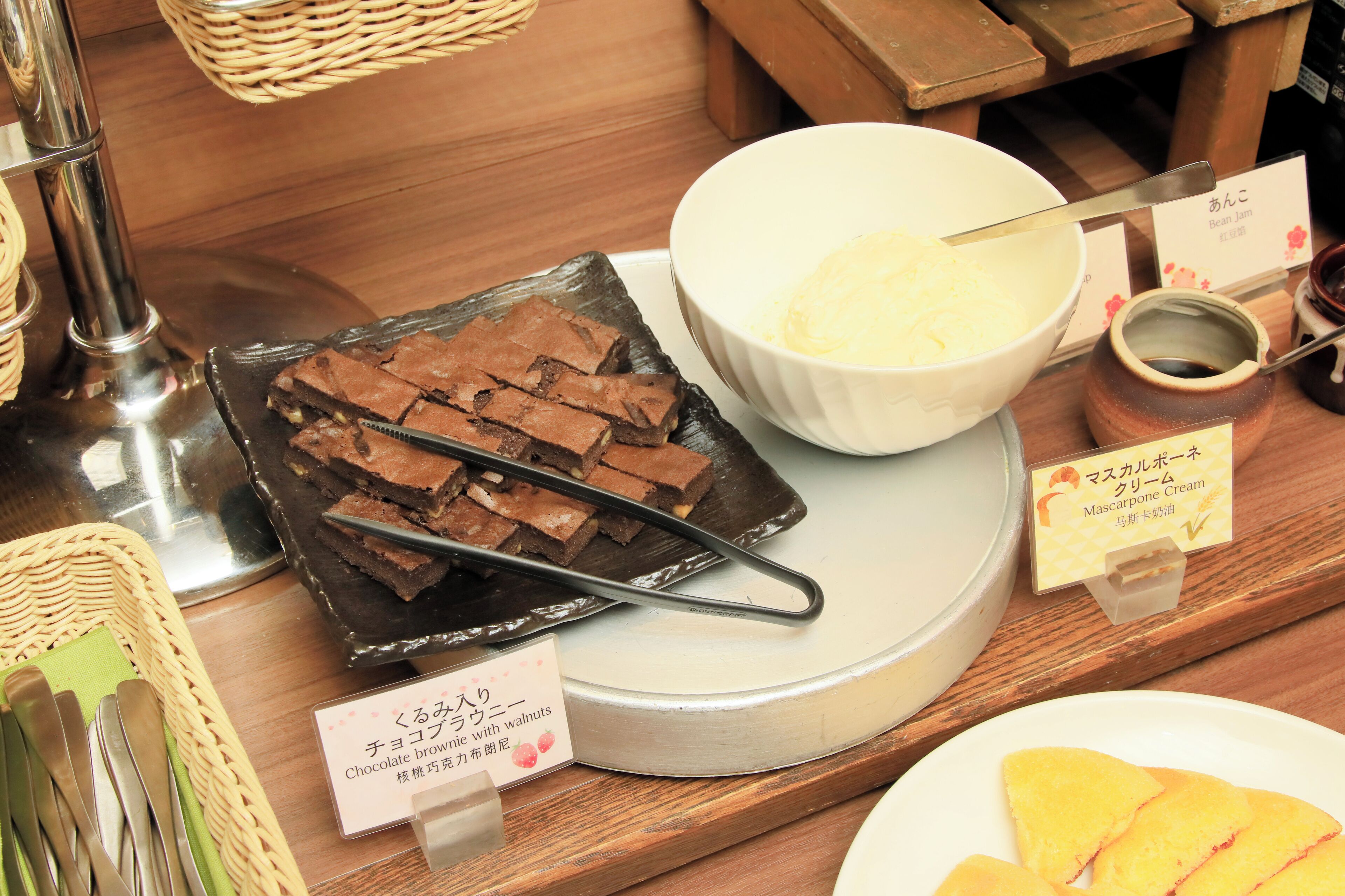 A dessert display with chocolate brownies, mascarpone cream, and a sign indicating a chocolate brownie with walnuts.