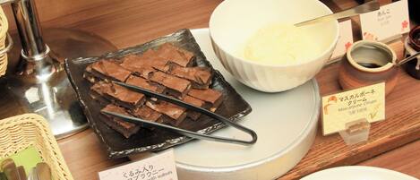 A dessert display with chocolate brownies, mascarpone cream, and a sign indicating a chocolate brownie with walnuts.