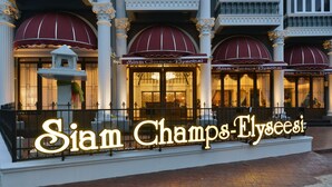 Exterior do hotel Siam Champs-Elysees, com suas marquises vermelhas características e arquitetura clássica.