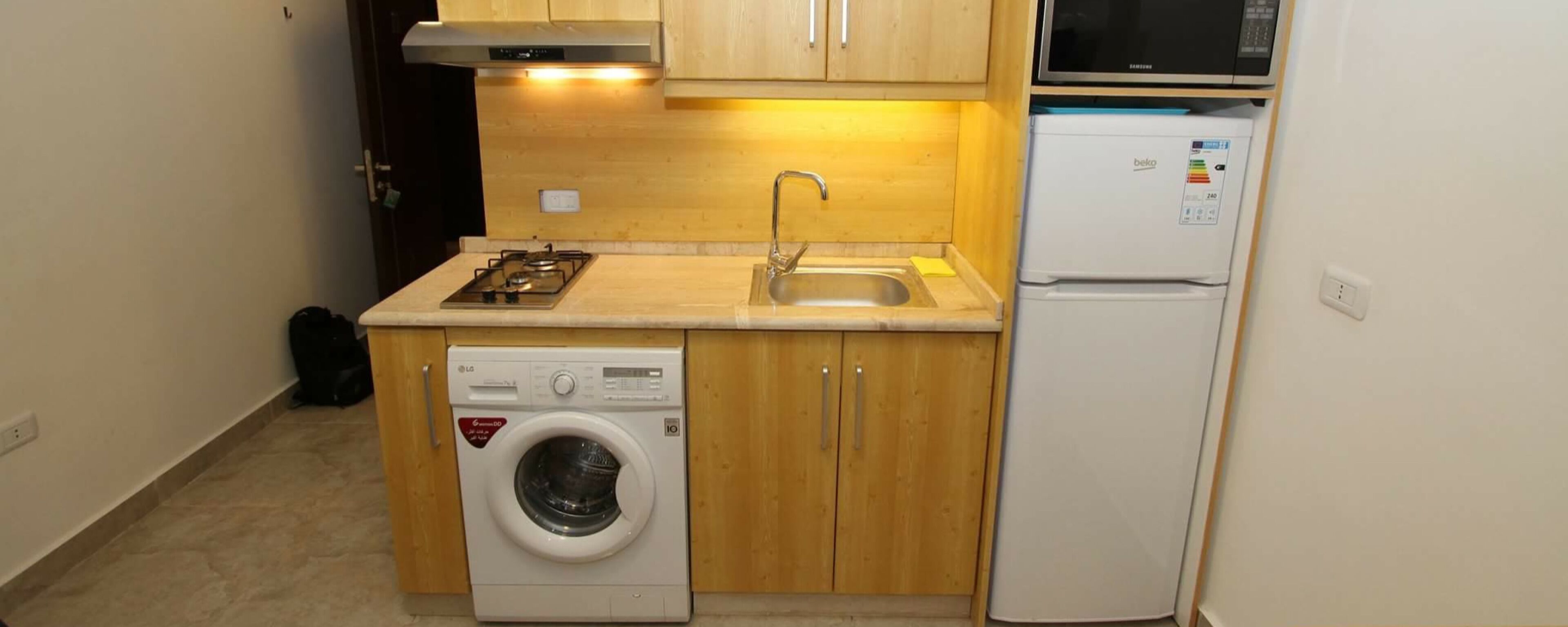 Cocina compacta con lavadora, refrigerador y microondas.