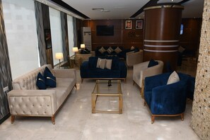 A modern lobby with plush seating, a central coffee table, and a large pillar. - Sparr Hotel (Amman)