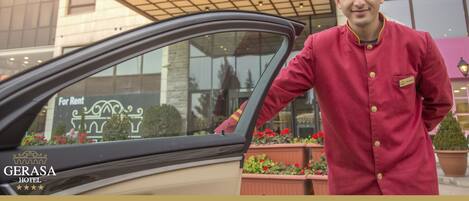 Entrada de un hotel con un cartel que dice "GERASA HOTEL" y un coche estacionado frente a él.