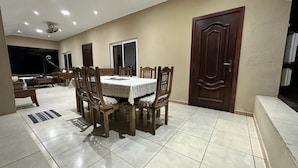 A dining area with a table and chairs, a ceiling fan, and a door. - GT Self Catering Apartments (Mahé Island)