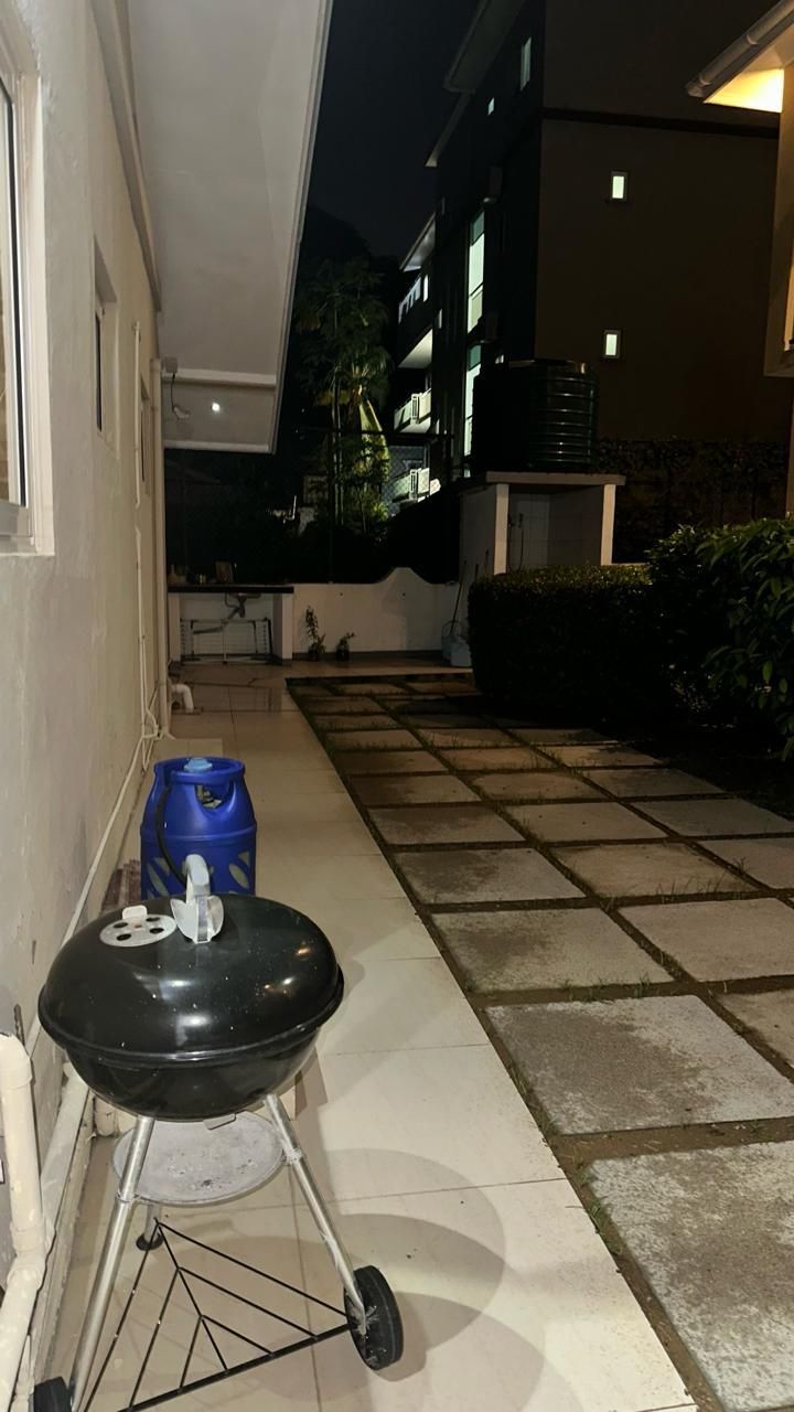 A narrow outdoor corridor with a grill and a blue container.