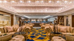 Un hall d’entrée luxueux, doté de canapés en cuir moelleux, d’un tapis à motifs et de lustres décoratifs.