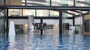 Un espace piscine intérieur moderne doté d’un grand écran diffusant un événement sportif.