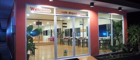 A modern building with a 'Welcome' sign and 'Nth Airport Resort' sign. It has a ramp for accessibility, large windows, and indoor seating visible.