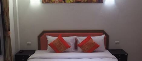 A hotel room with a bed, two nightstands, a wall-mounted painting, and a curtain.