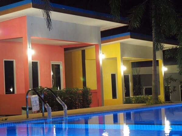 A hotel with a pool, featuring a modern design with colorful facades and a well-lit exterior.