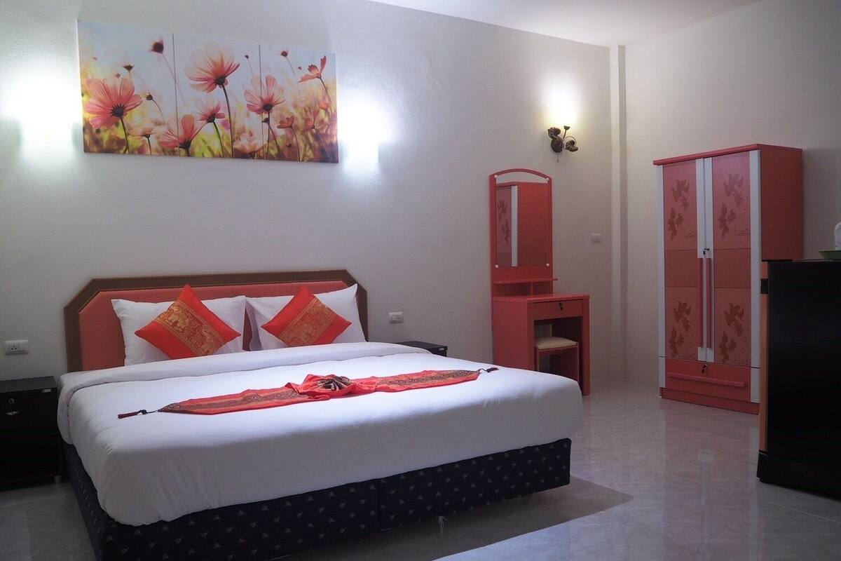 A bedroom with a bed, a dresser, a mirror, and a painting on the wall.
