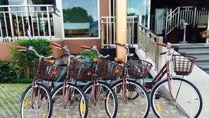 Four bicycles parked in front of a building with a glass facade and a staircase.
