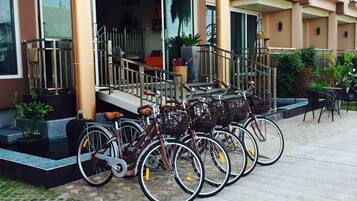 Una hilera de bicicletas estacionadas frente a un edificio de diseño moderno, con una escalera que conduce a una puerta y un área de estar al aire libre.