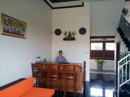A reception area with a wooden desk, chairs, a couch, clocks, and a staircase.