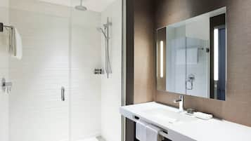 A modern bathroom with a glass shower enclosure, a white sink, and a large mirror.