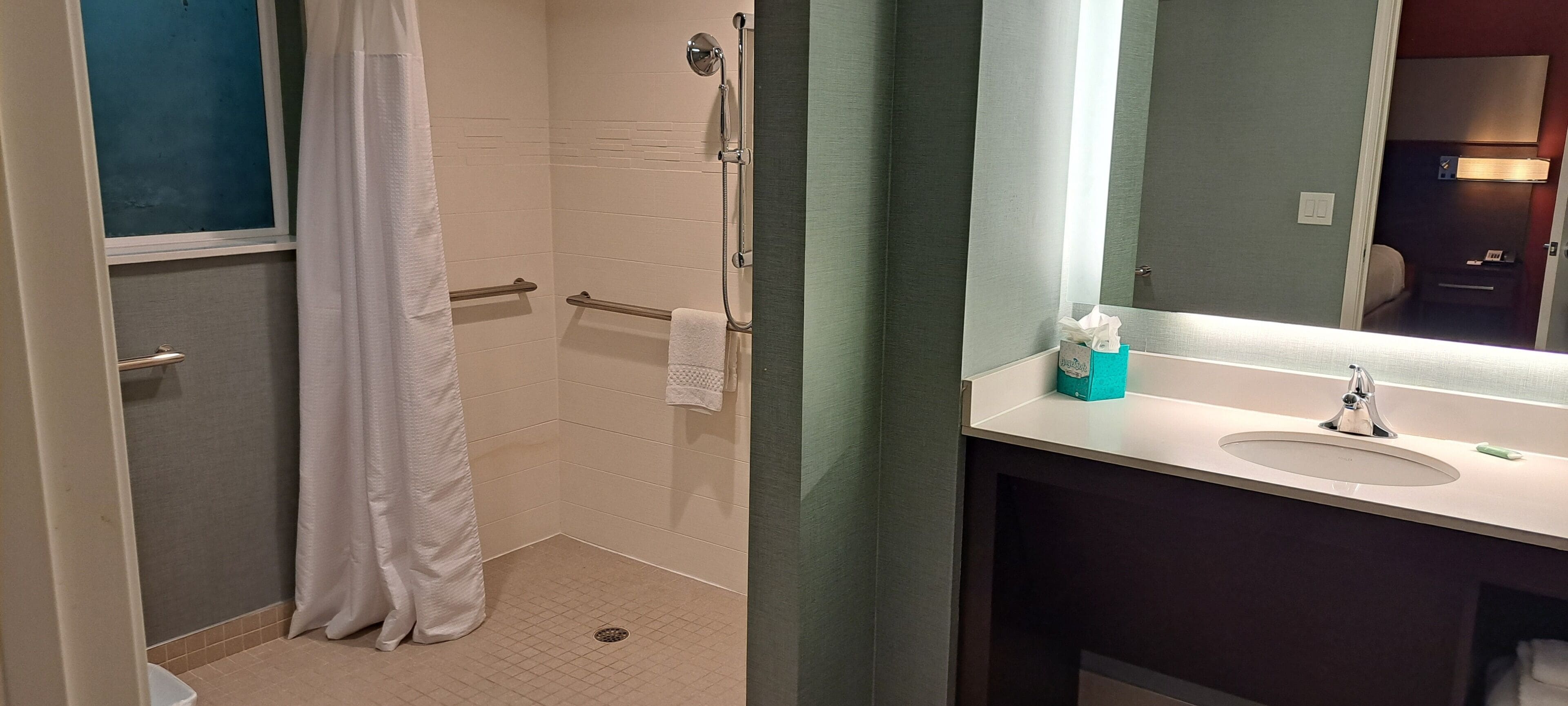 A bathroom with a shower, a sink, and a mirror.