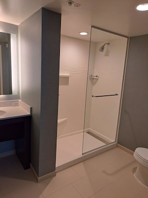 Une salle de bain moderne avec une douche à parois de verre, un lavabo blanc et des toilettes.