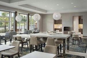 Un comedor moderno de hotel con ventanas amplias, varias mesas y sillas.