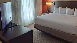 A hotel room with a bed, a desk with a computer, a nightstand, a lamp, and a window with curtains. - Residence Inn Columbia West/Lexington (West Columbia)