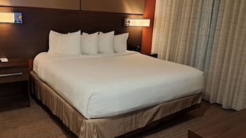 Habitación de hotel con una cama grande, una mesita de noche con un teléfono y una cortina.