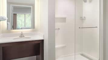 A bathroom with a glass-enclosed shower, a white sink, and a mirror with a towel rack.