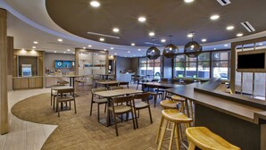 Een modern restaurant met een golvend ontwerp, houten meubels en een groot televisiescherm.