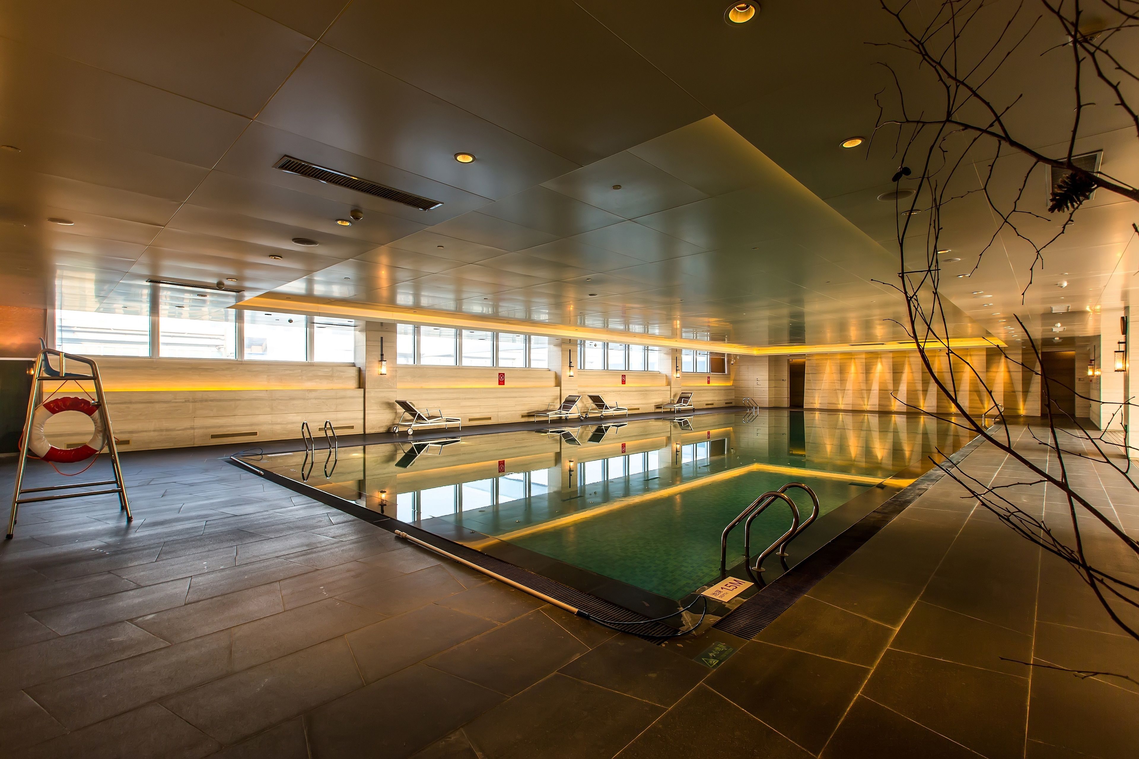 Una gran piscina interior con varias pistas de natación, una silla de salvavidas y una vista despejada del área de la piscina.