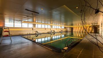 Una gran piscina interior con varias pistas de natación, una silla de salvavidas y una vista despejada del área de la piscina.