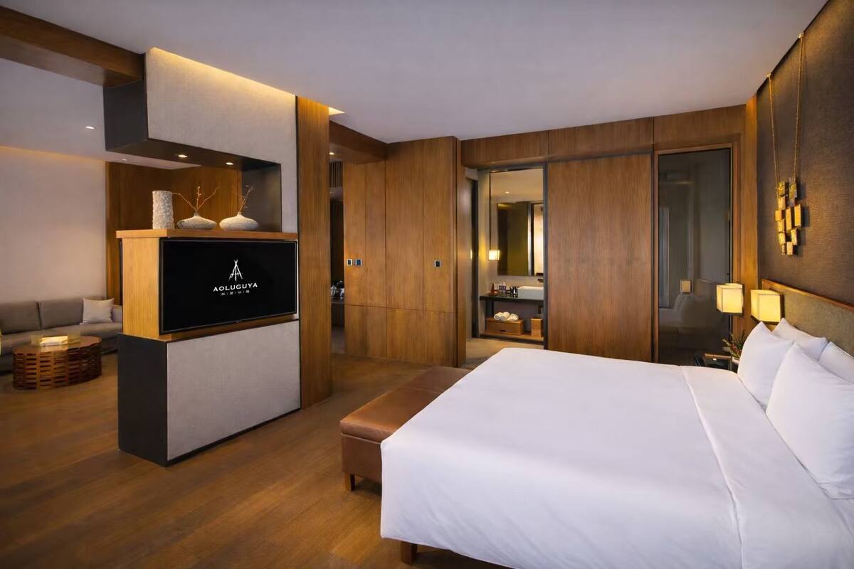 Ein Hotelzimmer mit einem Bett, einem Fernseher, einer Couch und einem durchgegangenen Tür erkennbaren Badezimmer.