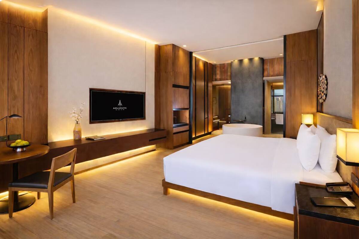 Ein modernes Hotelzimmer mit einem großen Bett, einem Schreibtisch mit Stuhl, einem Flachbildfernseher und einer Minibar.
