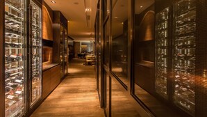 A corridor with glass-fronted wine storage units on both sides, wooden flooring, and recessed lighting. - AOLUGUYA · The Unbound Collection by Hyatt (Harbin)