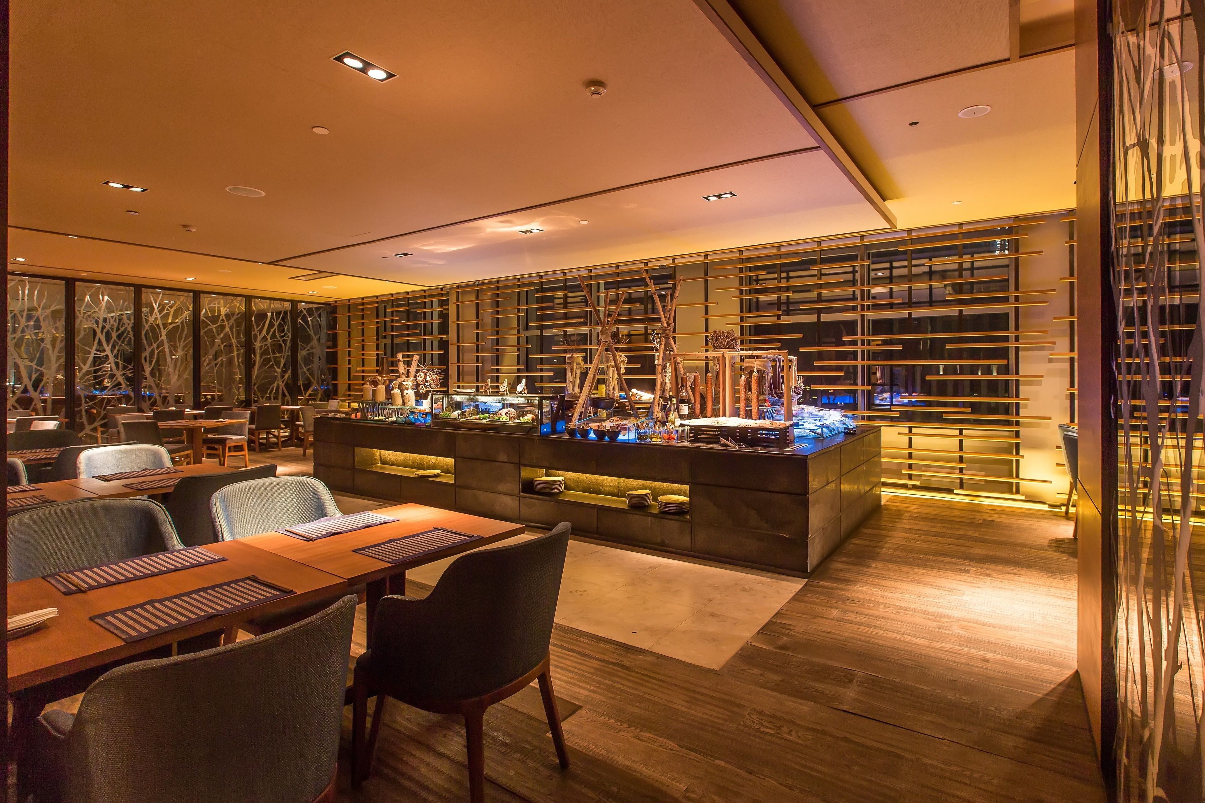 A modern restaurant with a long counter, multiple seating areas, and a decorative wall with vertical lines.