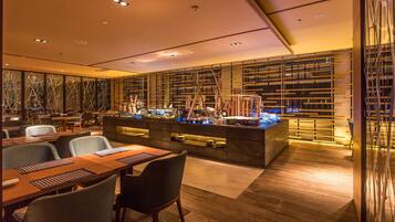 A modern restaurant with a long counter, multiple seating areas, and a decorative wall with vertical lines.