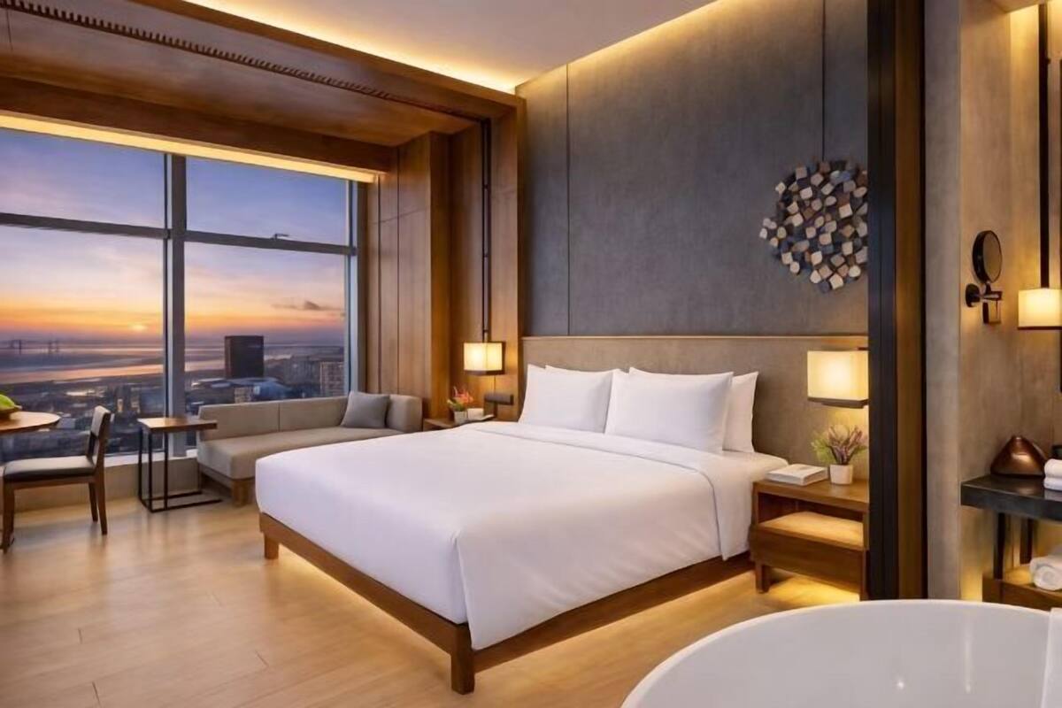 Ein Hotelzimmer mit einem großen Bett, einer Sitzecke, Blick auf die Stadt und einer Badewanne.