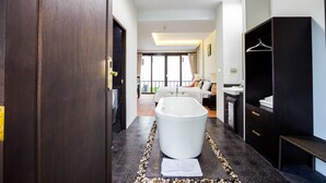 A modern bathroom with a freestanding bathtub, a walk-in shower, and a vanity with a sink. - Jamadevi Hotel (Lamphun)