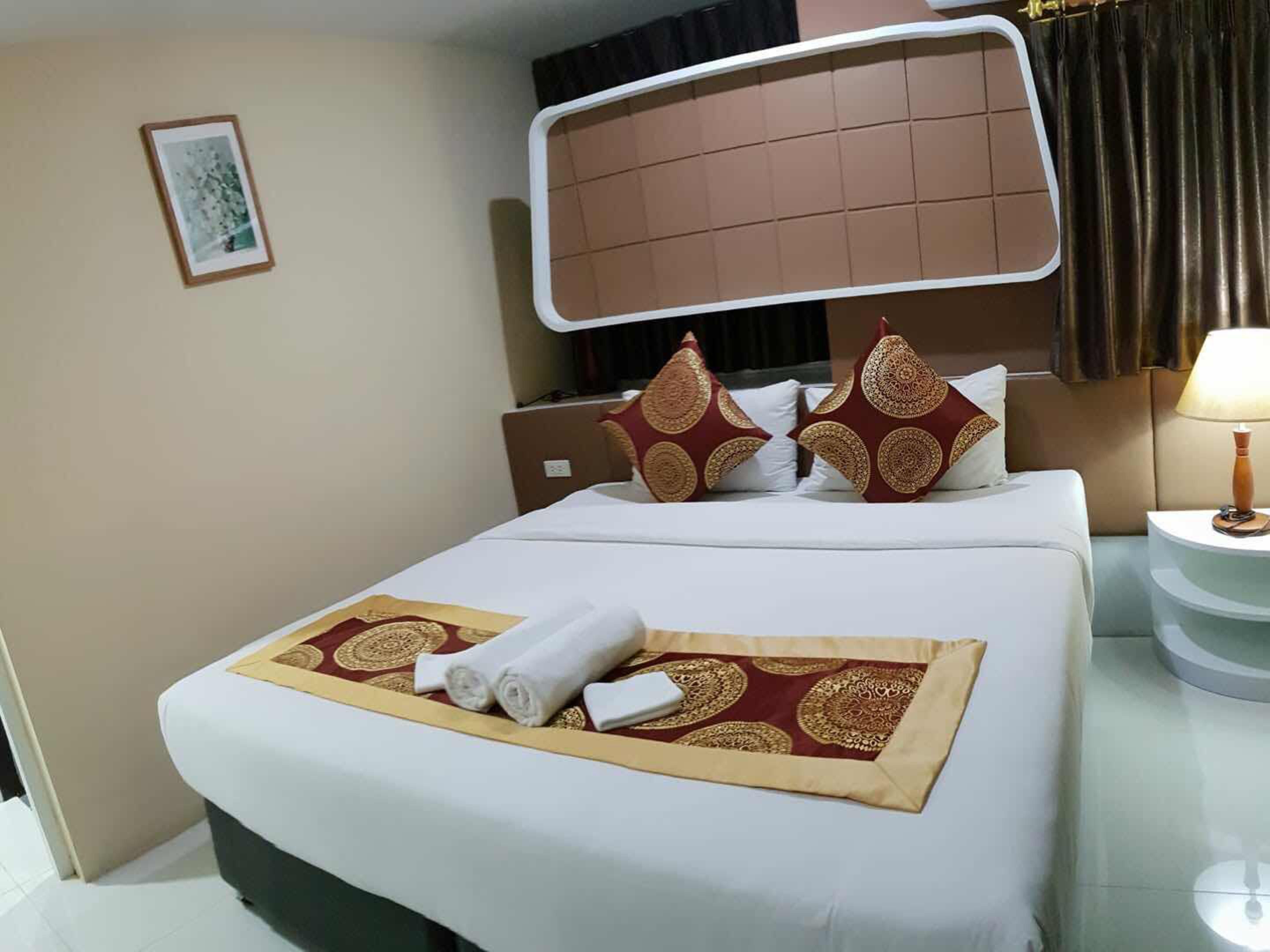 A hotel room with a bed, a bedside table with a lamp, and a headboard.