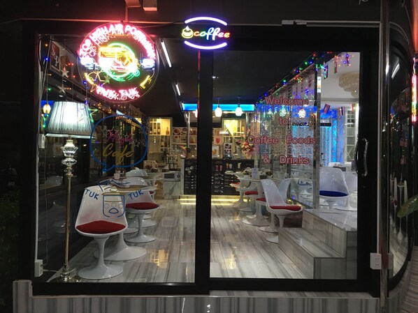 L’intérieur d’un café, avec un panneau néon, un comptoir et un espace salon.