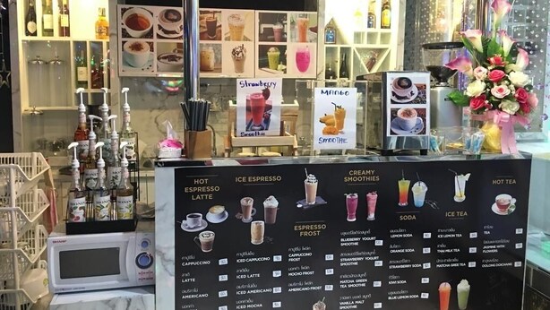 Un café où l’on peut consulter un tableau affichant les différentes boissons proposées, ainsi qu’un assortiment de machines à expresso.